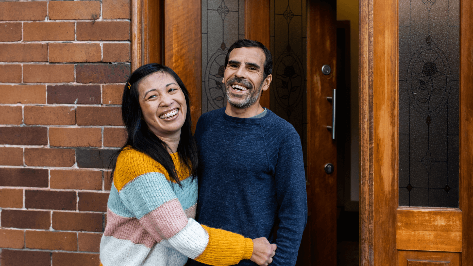 Couple embracing outside their home